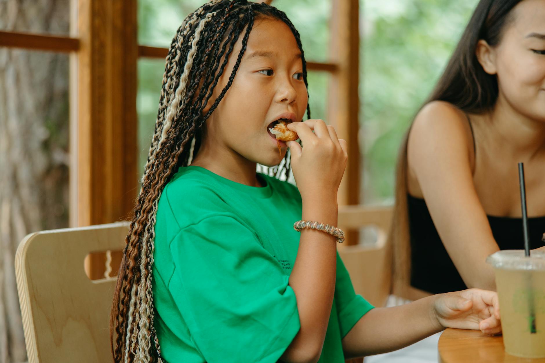 Dziewczynka z warkoczem je posiłek w domu, ćwicząc gryzienie i żucie