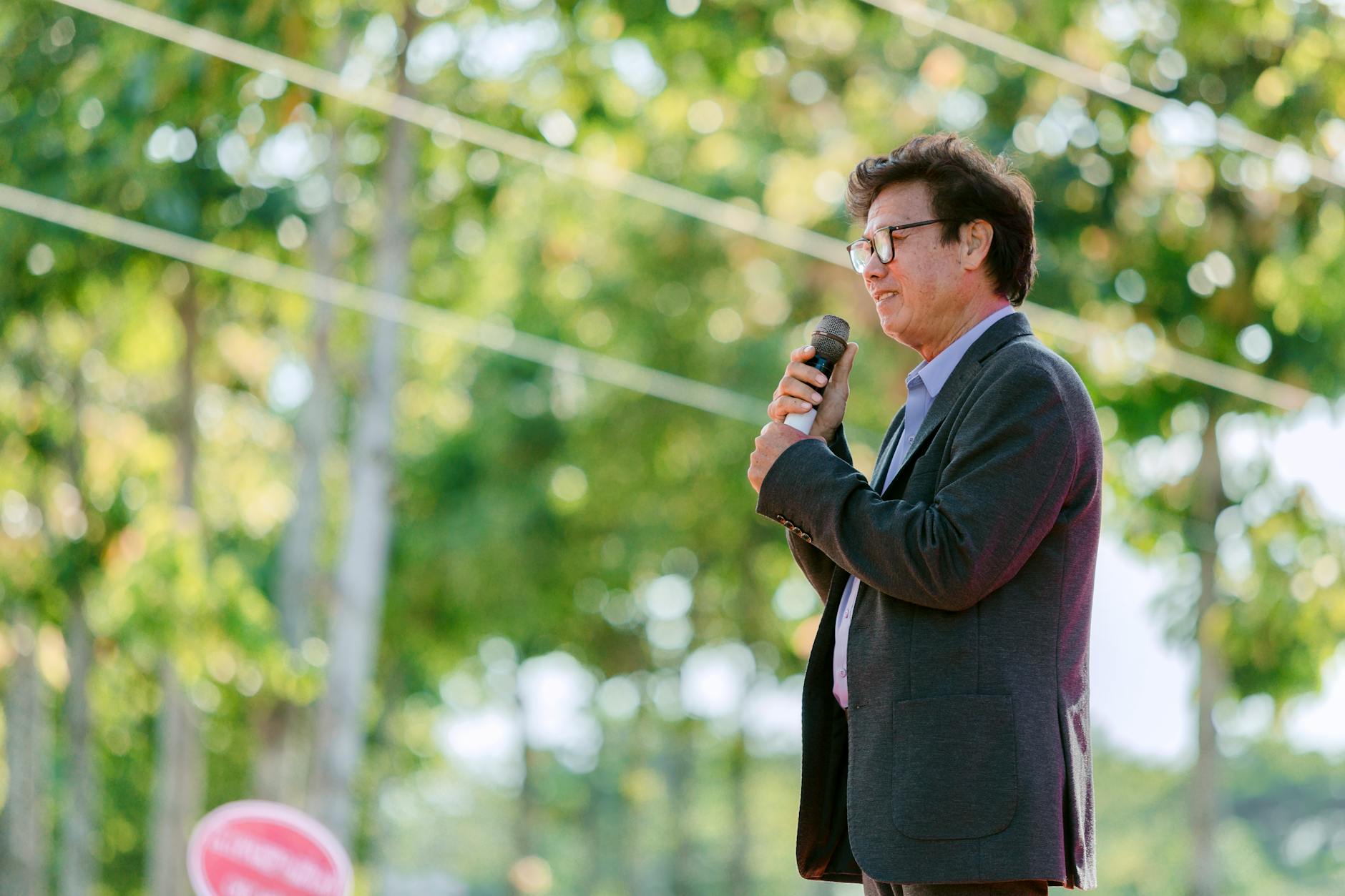 Mężczyzna pewnie przemawia do mikrofonu w parku