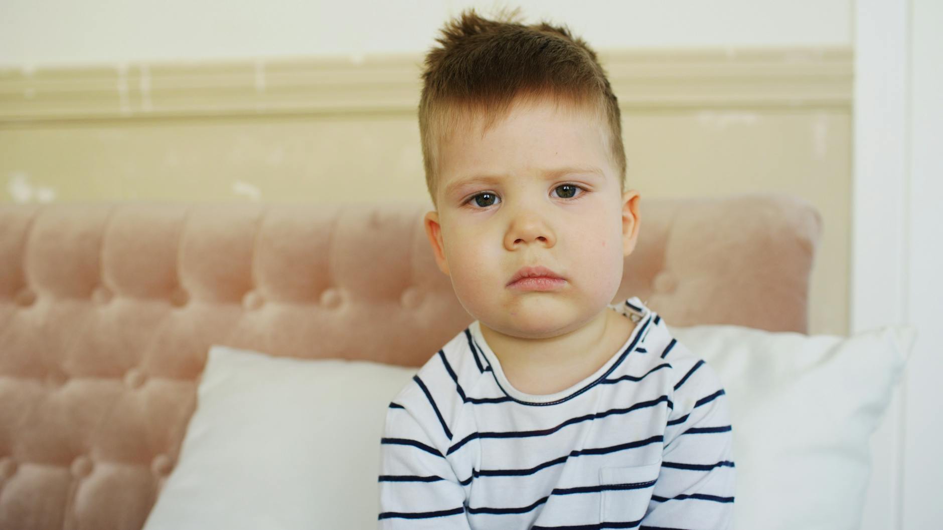 Smutny mały chłopiec siedzący na kanapie w domu