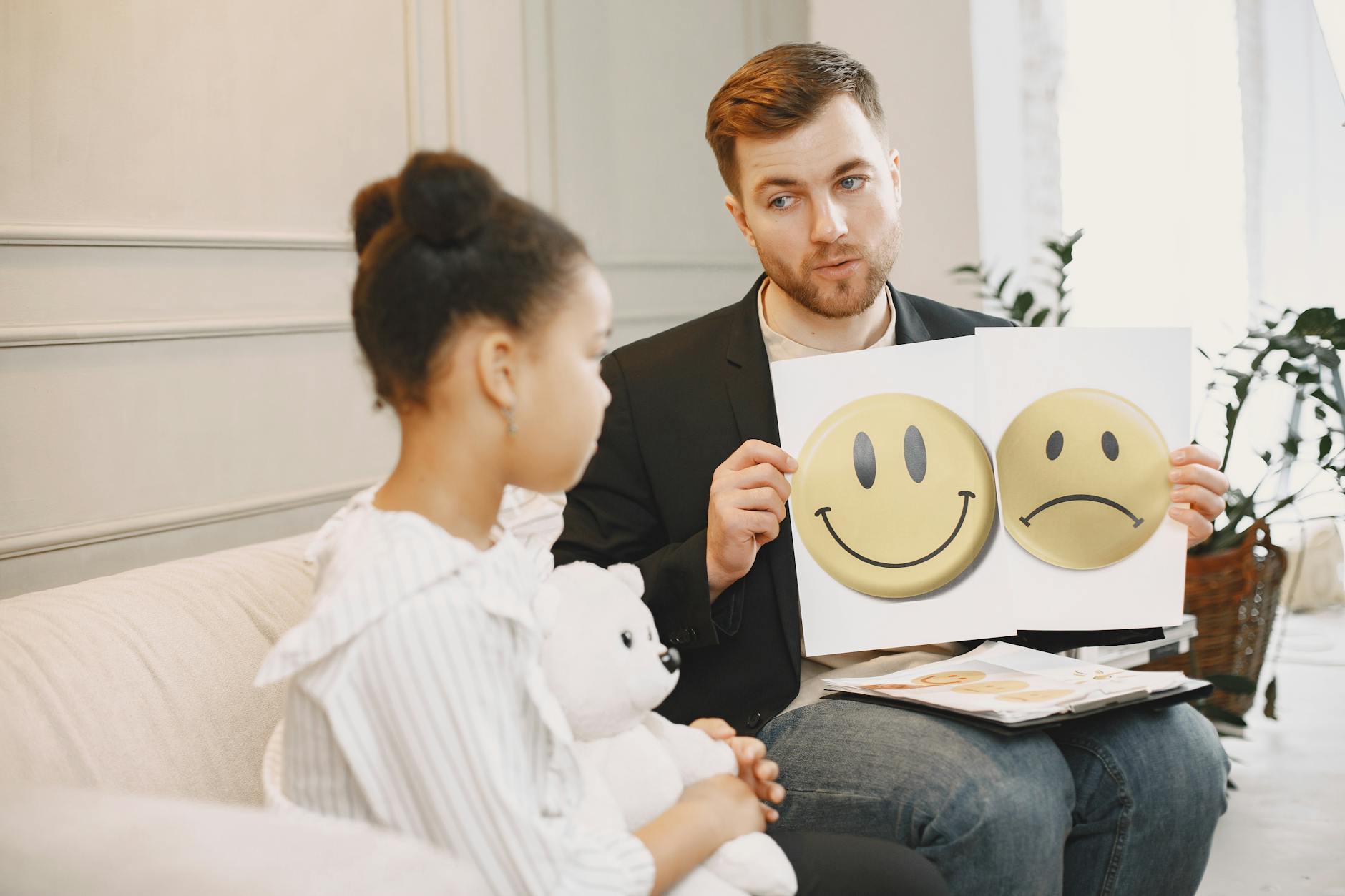 Terapeutka z kartami emocji rozmawia z dzieckiem podczas zajęć