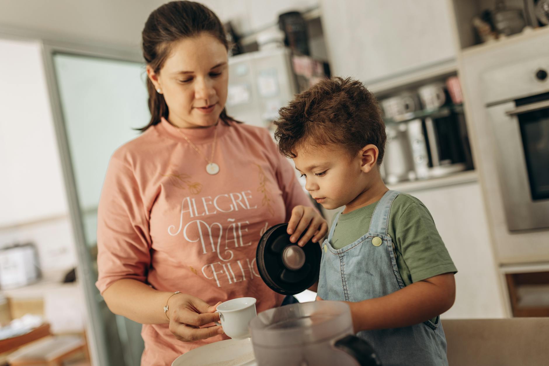 Dlaczego dziecko powtarza sylaby? Przyczyny i wsparcie w domu Mama z synem w kuchni razem nalewają napój