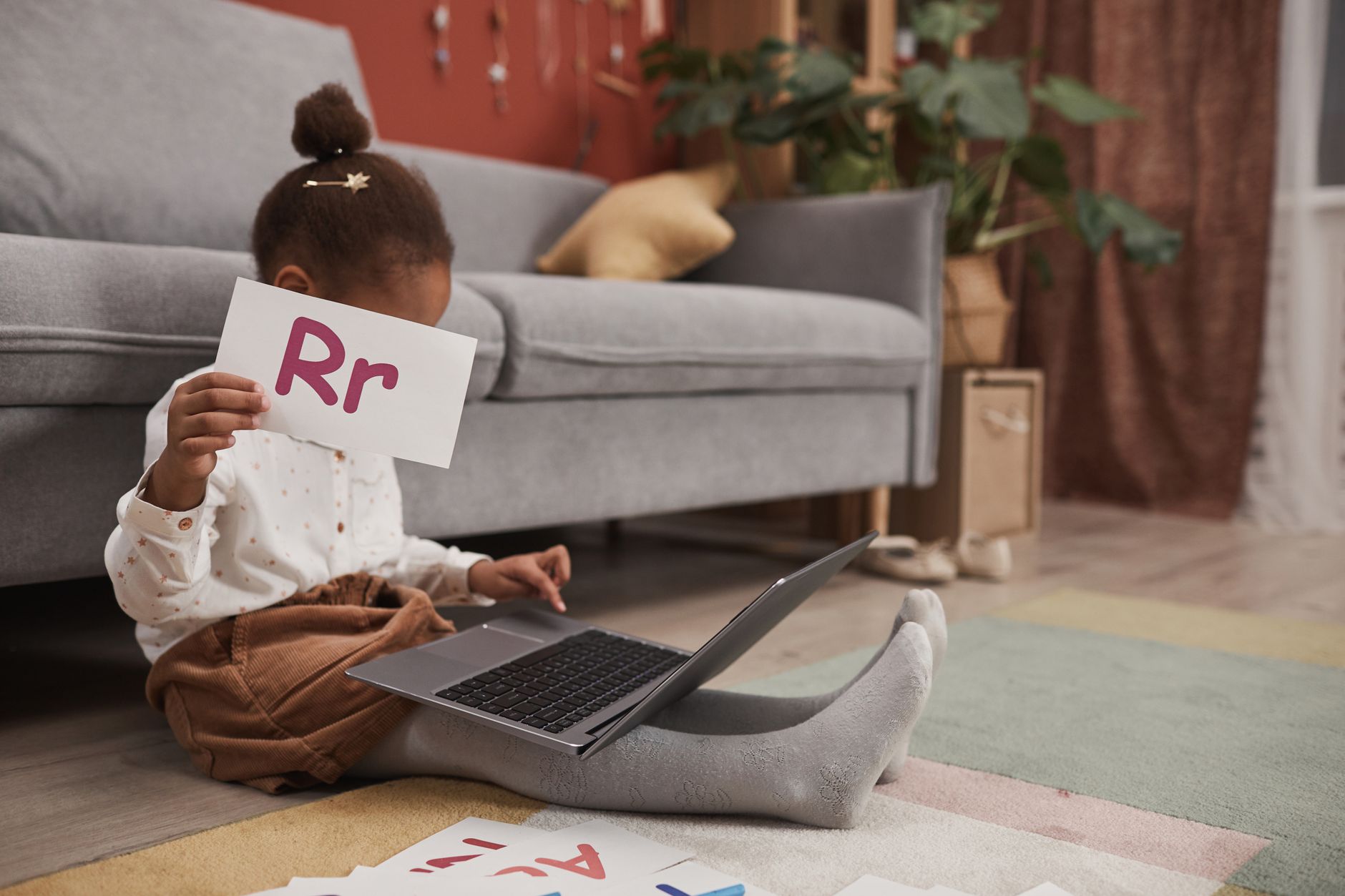 Dziecko bawi się kartami z literami i uczy online przy laptopie